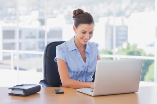 Happy businesswoman working on her laptop