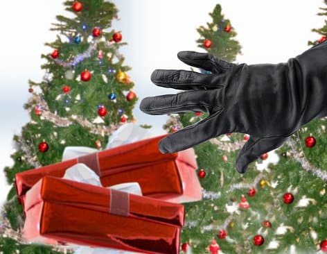 gloved black hand of a thief stealing Christmas gifts next the Christmas trees