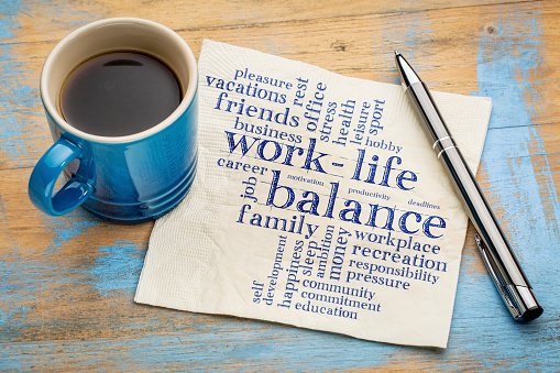 Coffee and pen next to napkin that has work-life balance written on it